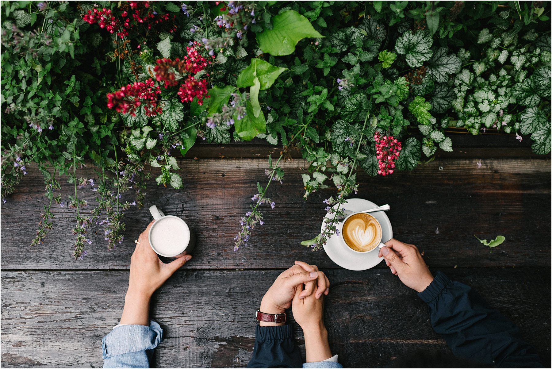 A couple holding hands with a latte.